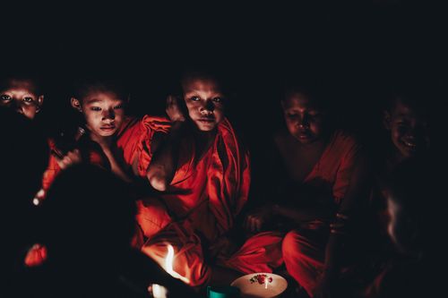 Free A group of young monks in Cambodia illuminated by candlelight during a serene gathering. Stock Photo