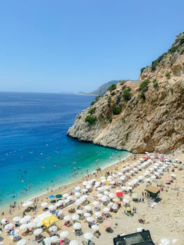 Stunning aerial view of Kaputaş Beach with vibrant blue waters and sunbathers in Antalya, Türkiye.