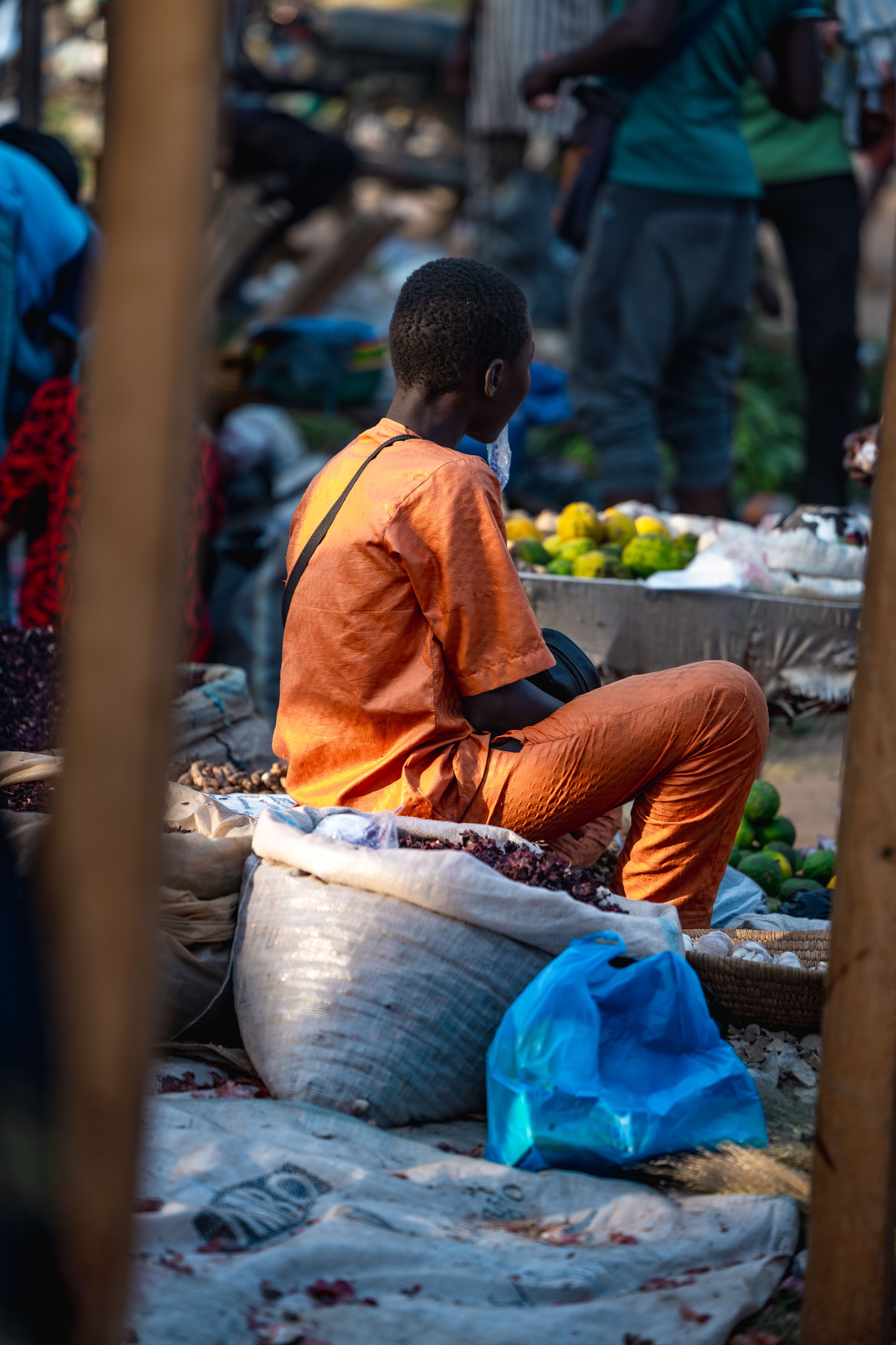 Un jeune garçon assis devant son étal coloré au marché
