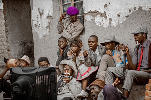 A group of people in vintage attire enjoying outdoor TV viewing in Malawi.