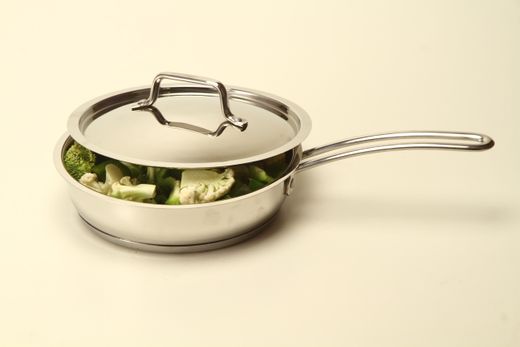 Stainless steel saute pan with lid holding broccoli and cauliflower florets