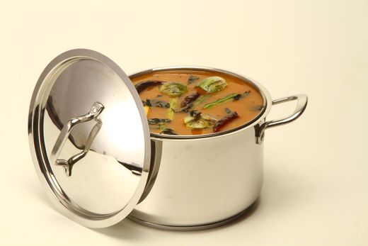 Polished stainless steel pot with two loop handles, soup, lid leaning