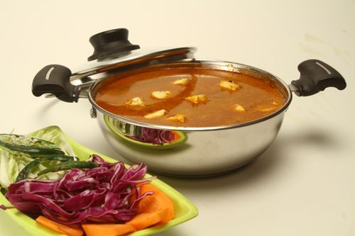 Free Indian paneer curry in a pot with fresh vegetables on the side, perfect for a hearty meal. Stock Photo