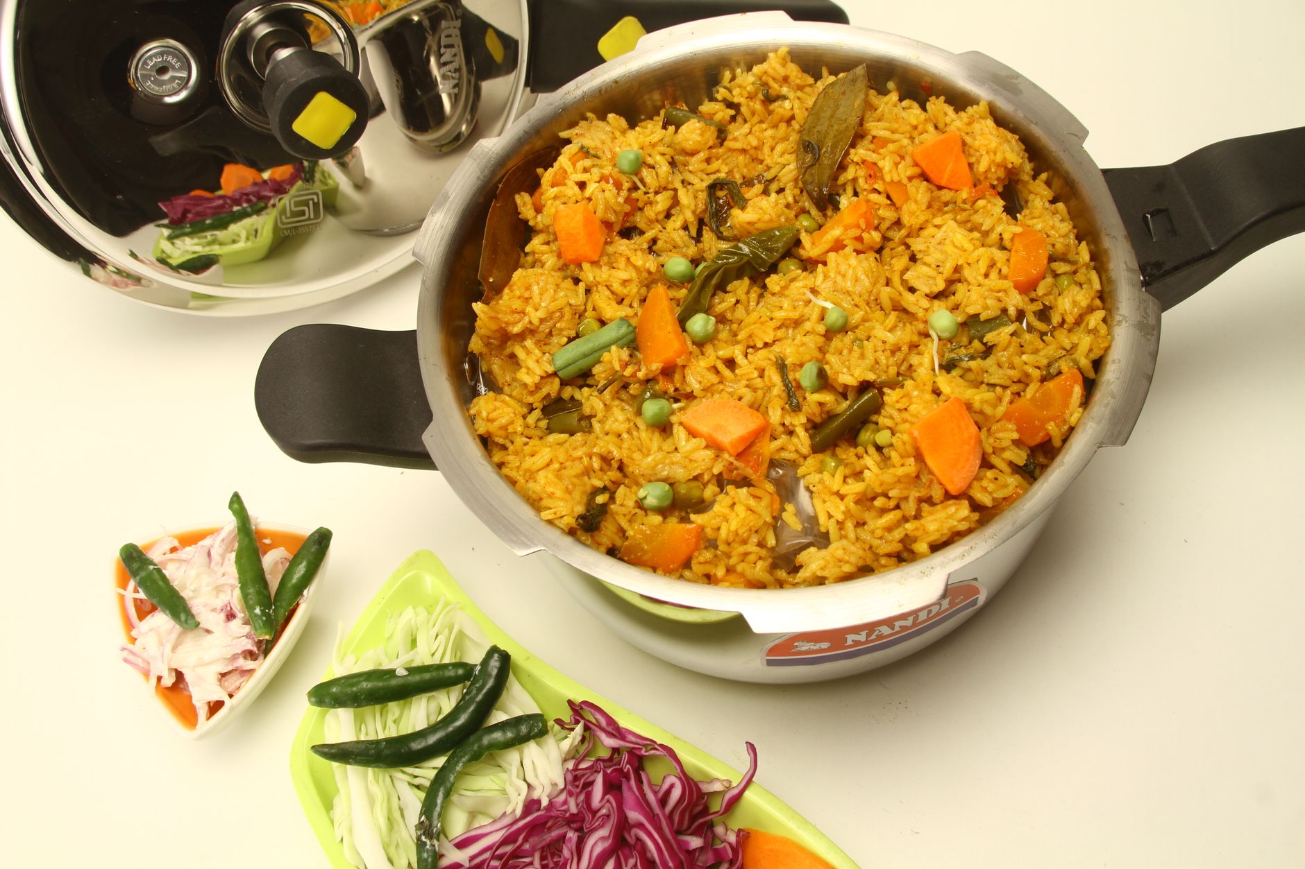 Delicious vegetable biryani served in a pressure cooker with fresh salad sides, ready to enjoy.