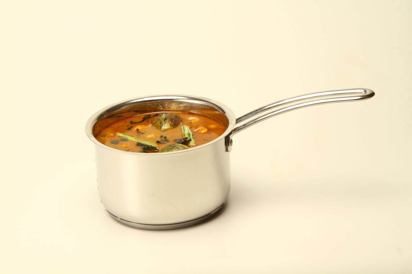 A vibrant South Indian sambar with vegetables in a stainless saucepan, ideal for culinary themes.