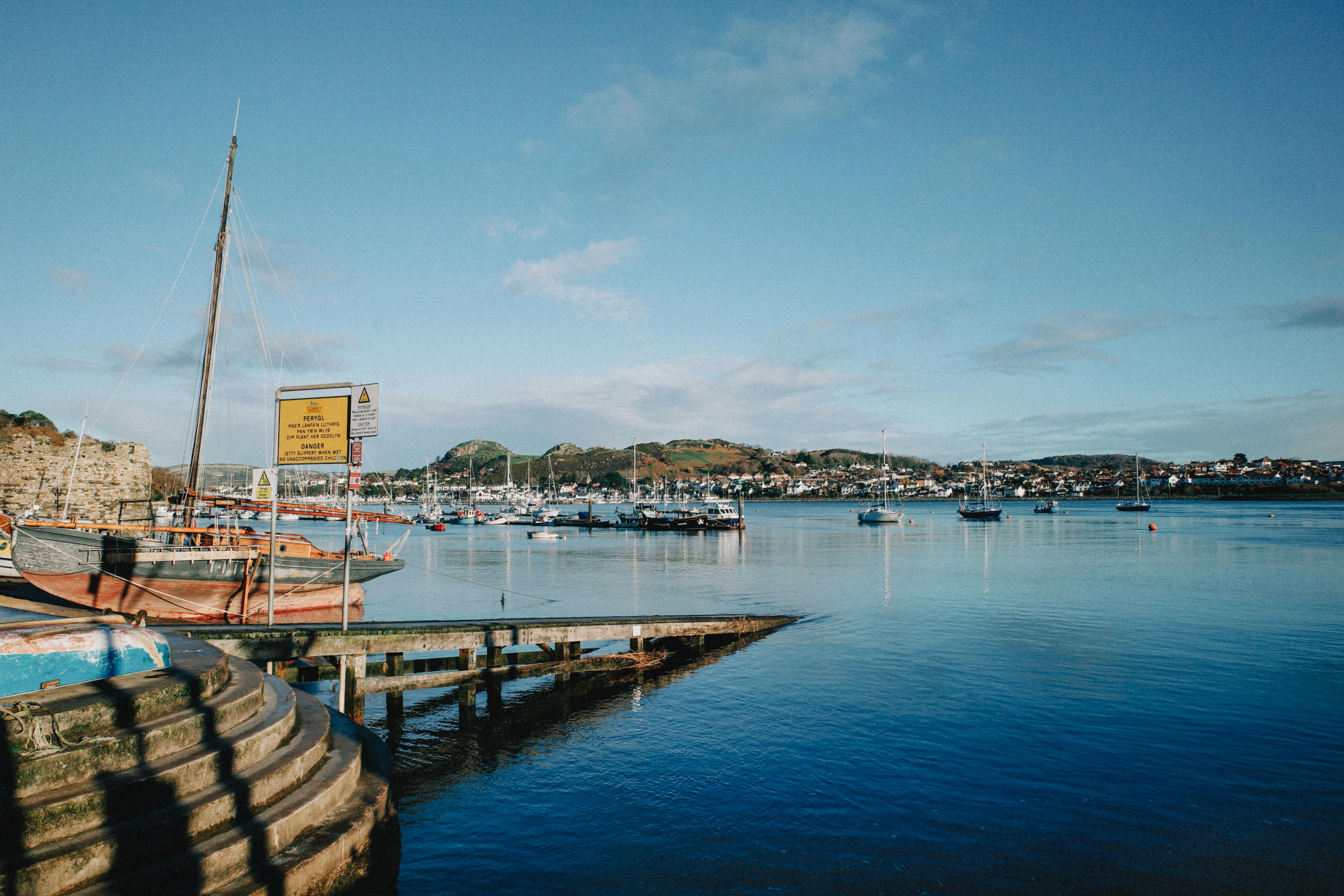 Picturesque view of Conwy Harbor, Wales, with boats and vibrant waters on a clear day.