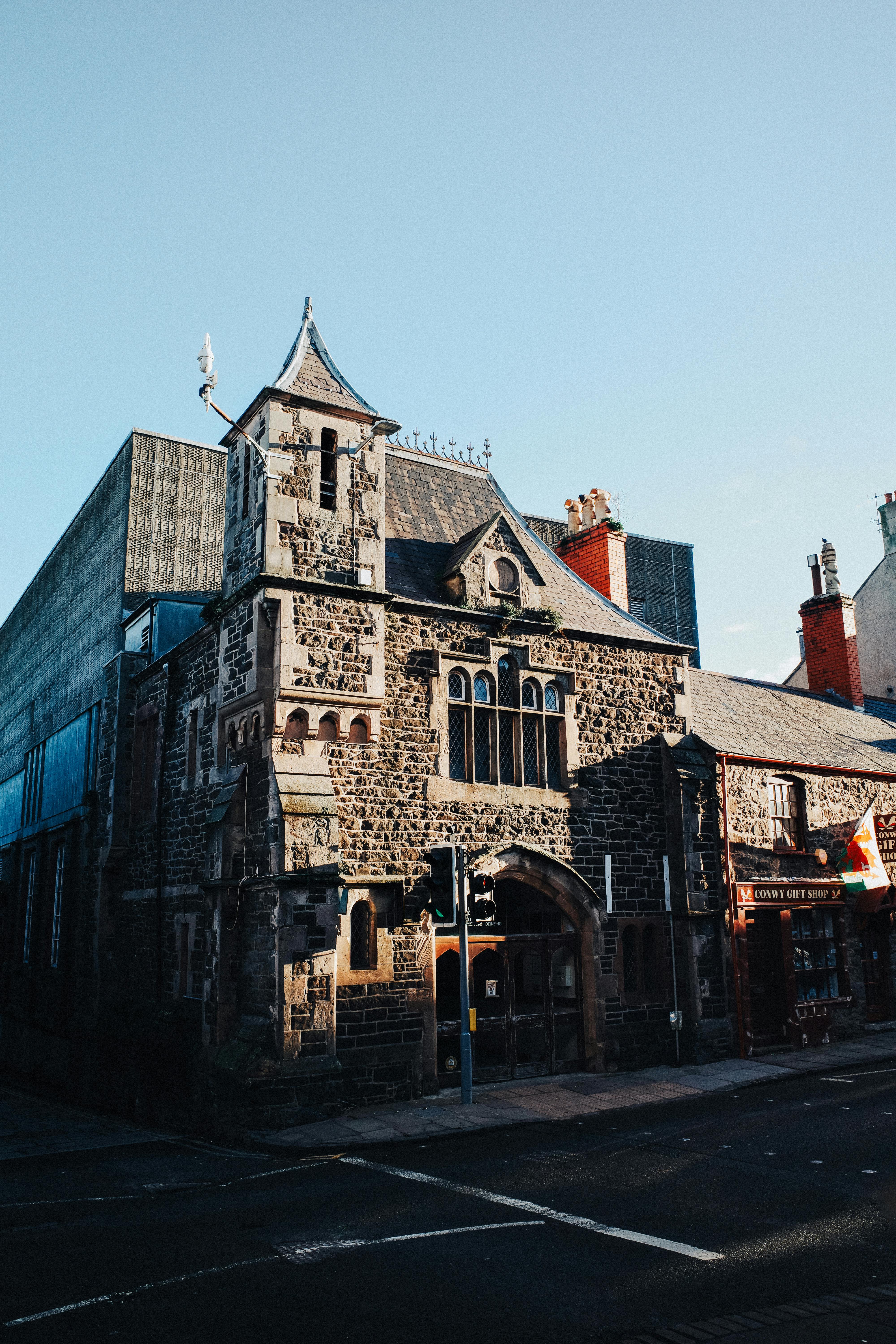 Captivating view of a historic stone building with Gothic architecture in Conwy, Wales, under a clear blue sky.