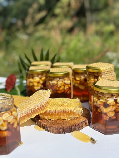Free Artisanal honey jars with honeycomb displayed in a lush outdoor setting, capturing natural beauty. Stock Photo