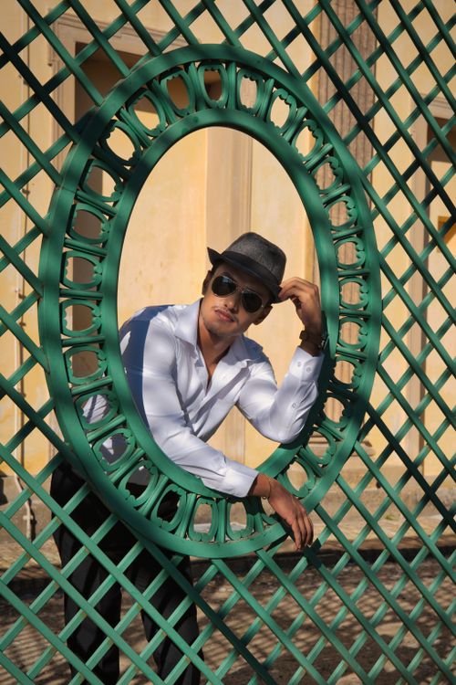 Free Young man in sunglasses and hat posing at a decorative outdoor structure in Potsdam, Germany. Stock Photo