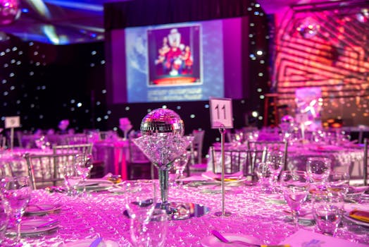 Lavish themed dinner setup with disco balls and purple lighting for a glamorous event.