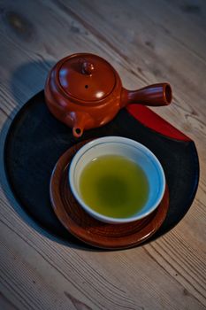 Overhead view of a Japanese tea set with green tea on a stylish tray, exuding calm and tradition.
