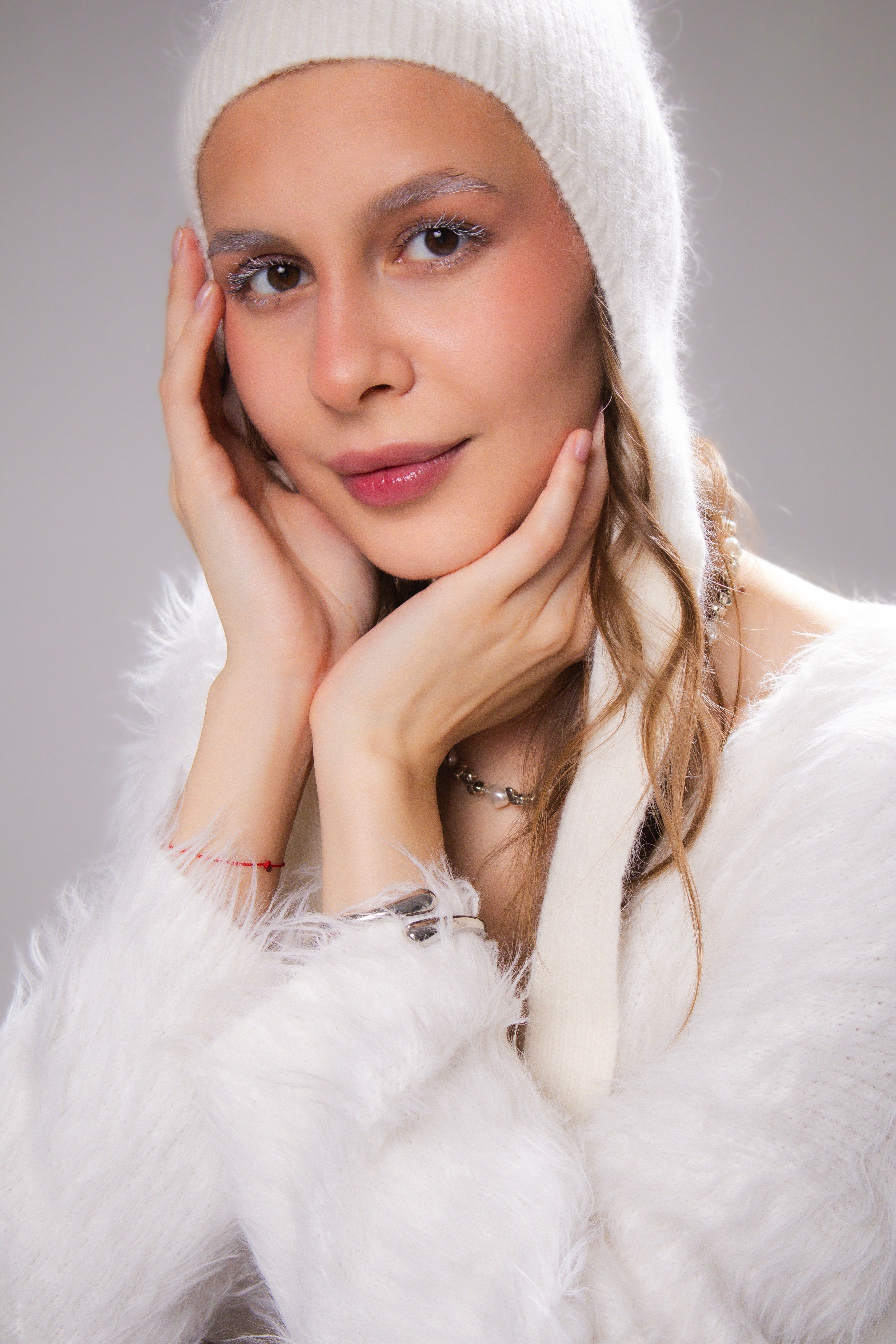 Elegant portrait of a woman in a white hat with a soft winter theme.