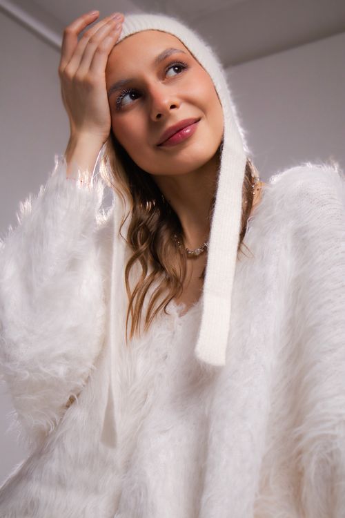 Free Stylish woman in a cozy white fluffy sweater and hat poses indoors. Stock Photo