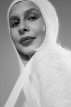 Stylish woman in a white fur hood smiling in a warm, elegant portrait.