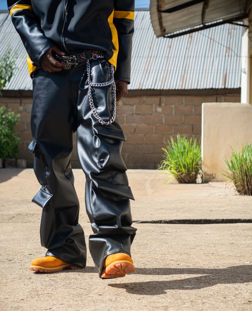 Free Stylish individual in leather pants with chain accessories portrayed in an urban setting. Stock Photo