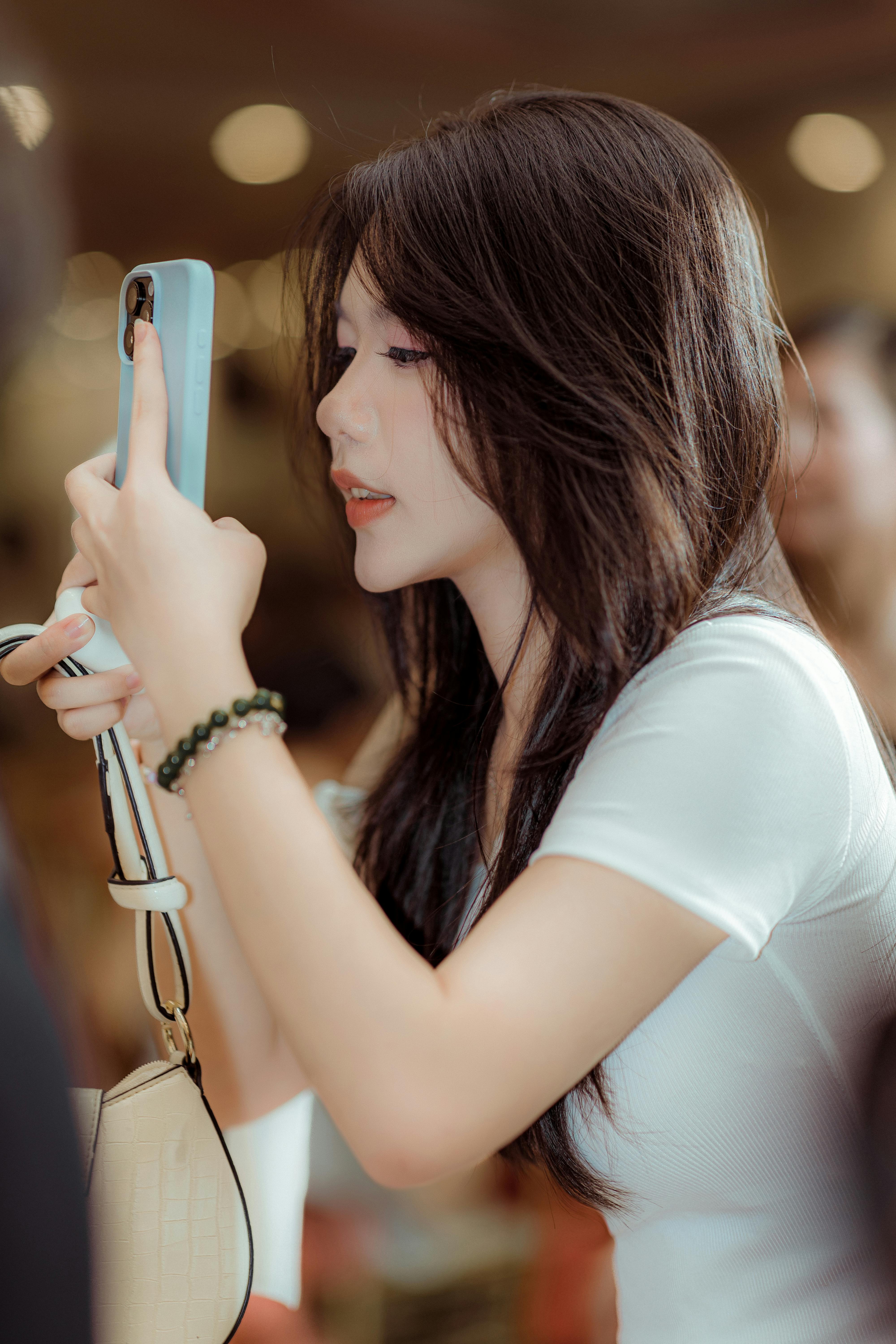 gratis Een jonge vrouw in een café gebruikt een smartphone en concentreert zich op de interactie met het apparaat. Stockfoto