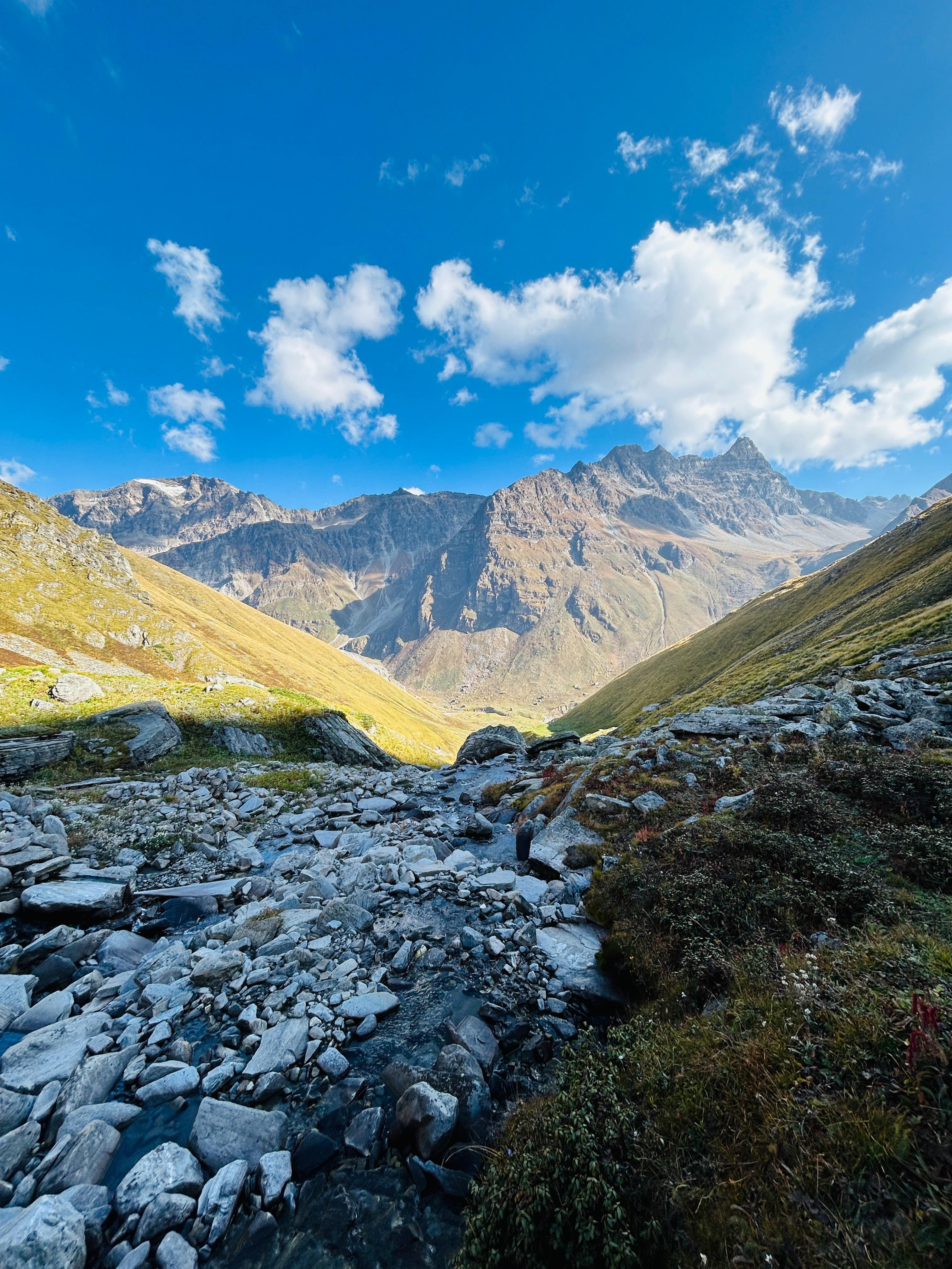 Breathtaking view of towering mountains under a bright blue sky and fluffy clouds.