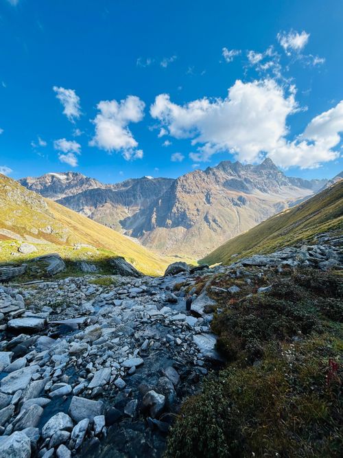 Free Breathtaking view of towering mountains under a bright blue sky and fluffy clouds. Stock Photo