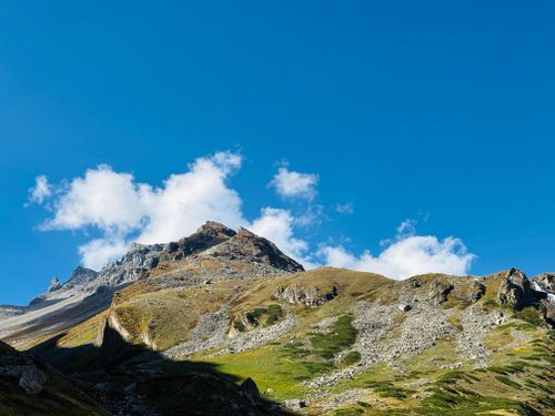 Free Majestic alpine mountain landscape under a vibrant blue sky with scattered clouds. Stock Photo