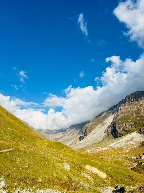 Free Scenic view of a lush green valley and majestic mountains under a bright blue sky. Stock Photo