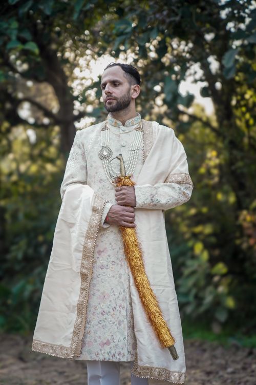 Free A man in traditional ceremonial attire holding a sword in an outdoor setting, exuding elegance and tradition. Stock Photo