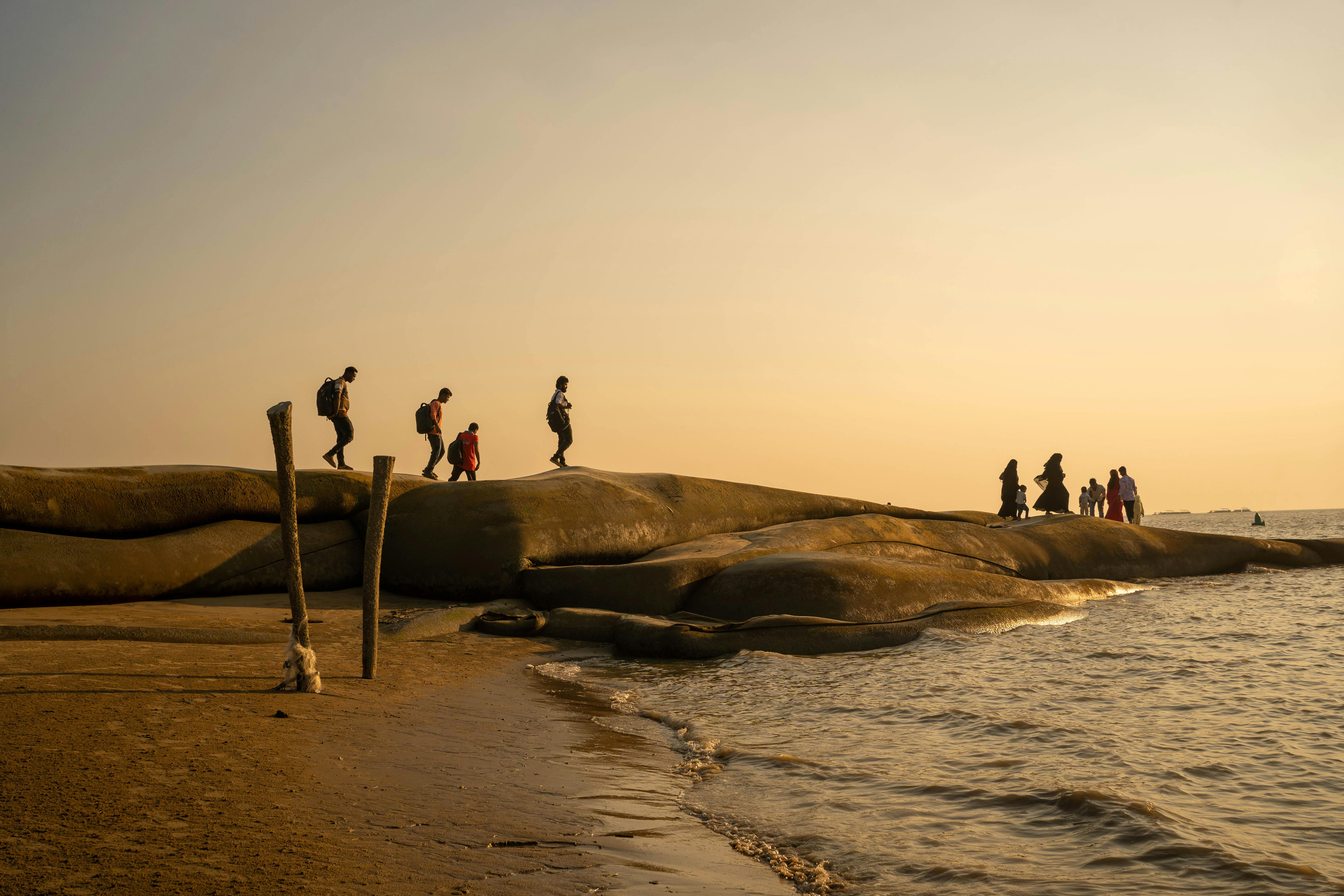 People enjoying a scenic walk along the beach at sunset in Chittagong, Bangladesh.
