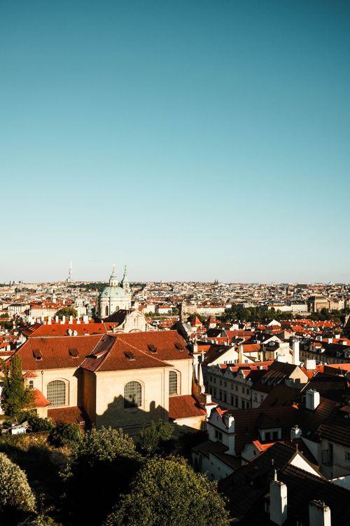 Free Scenic aerial view of Prague with red rooftops and historic landmarks under a clear sky. Stock Photo