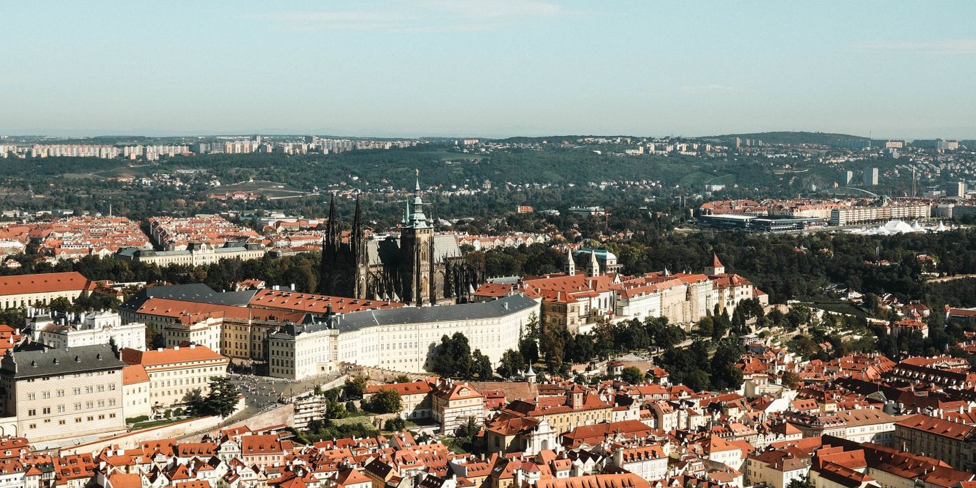 Aerial view of historic Prague cityscape with red rooftops and the castle
