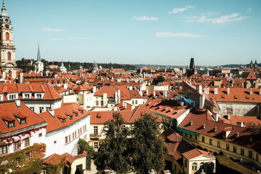 Explore the charming red-tiled rooftops of Prague's historic district under a clear blue sky.