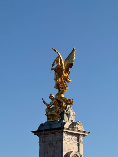 Free Golden statue atop the Victoria Memorial near Buckingham Palace against a clear blue sky. Stock Photo