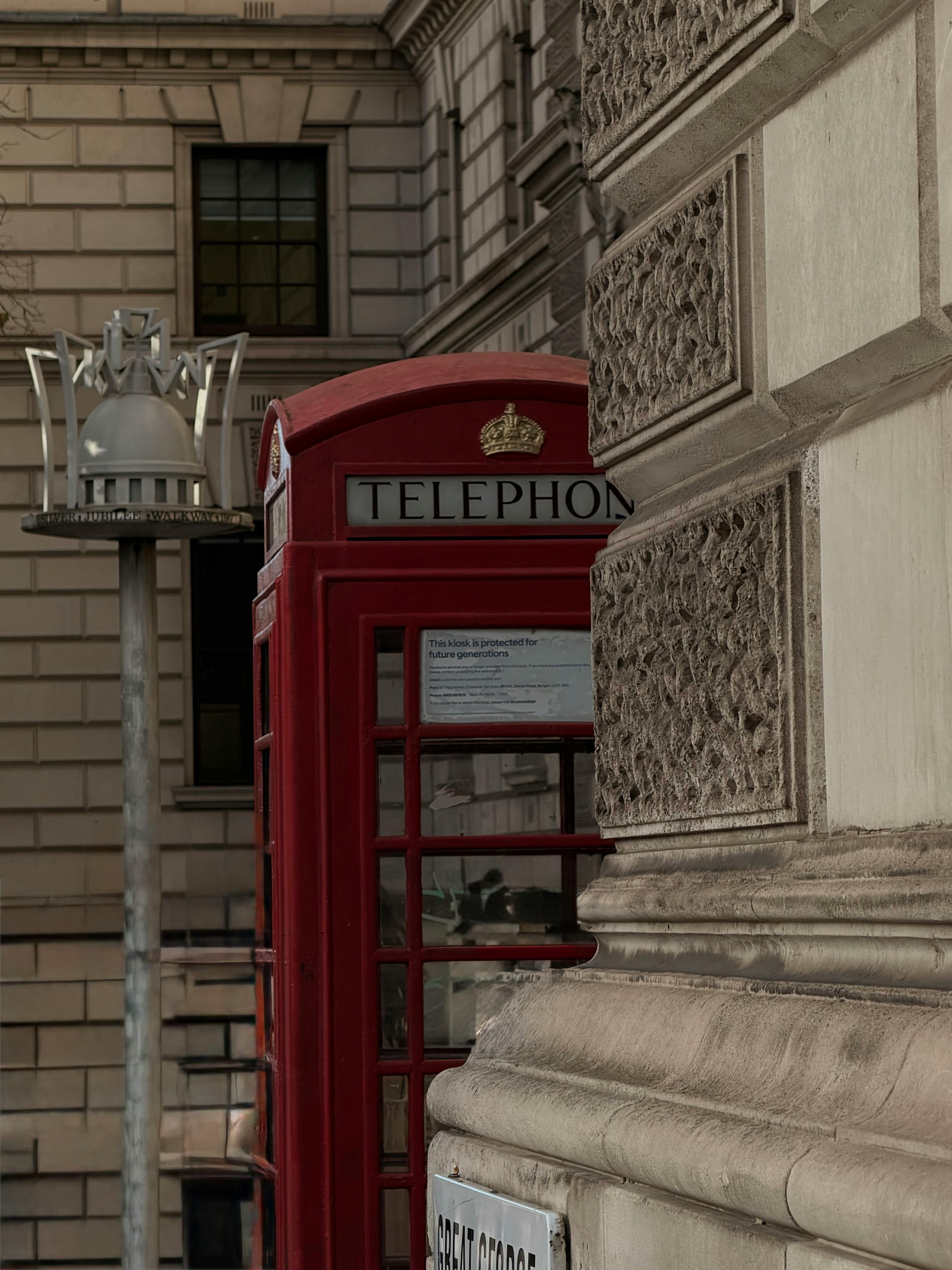 Gratis Classica cabina telefonica londinese vicino a un'architettura storica, che cattura l'iconica cultura britannica. Foto a disposizione