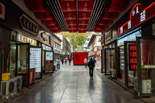 Vibrant shopping street in Luoyang, China with red banners and local shops.