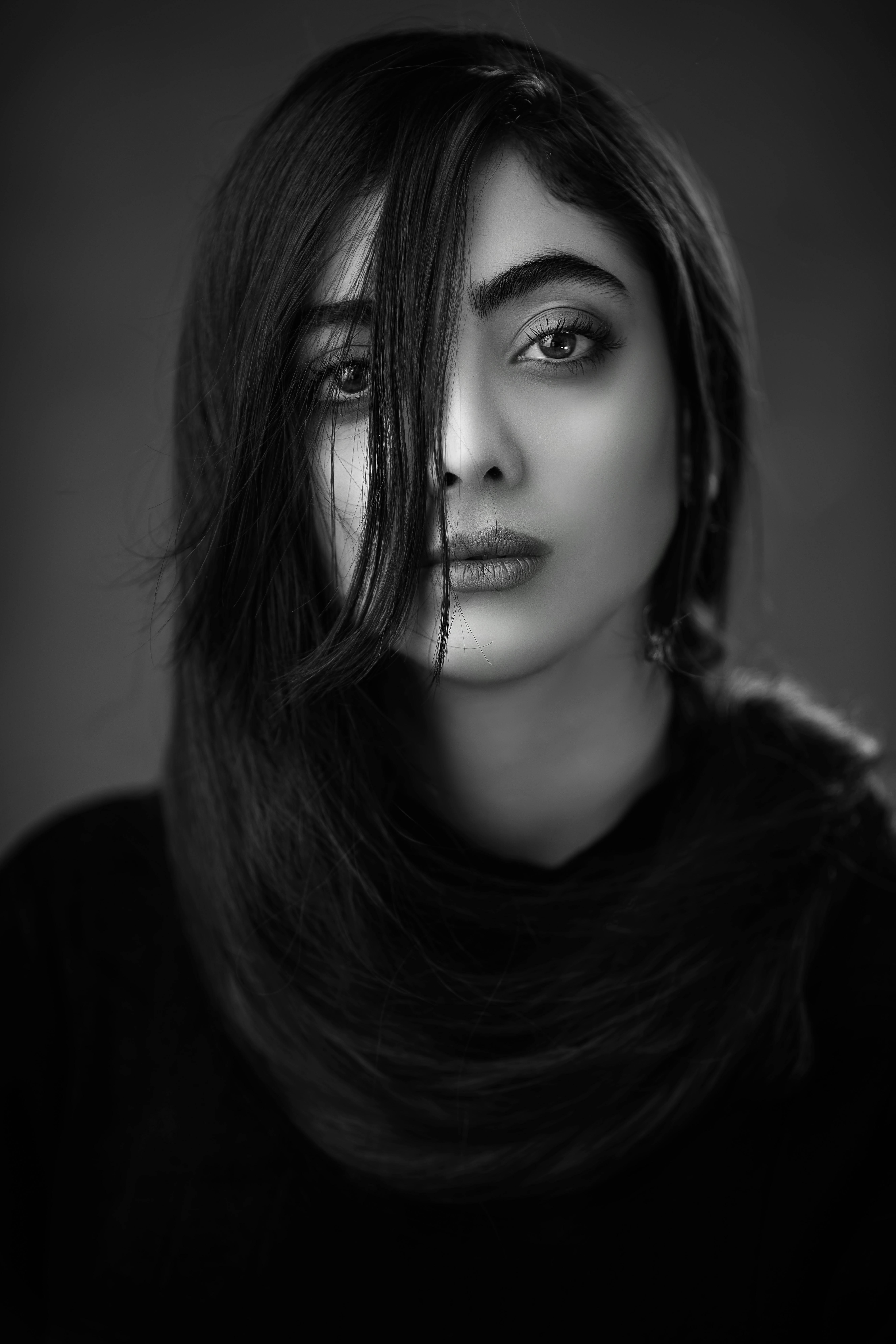 这幅迷人的黑白工作室肖像，描绘了一位面容引人注目的年轻女性