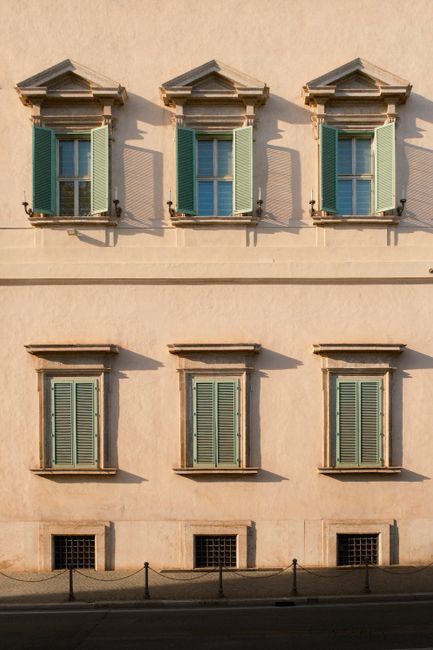Elegant facade with green shutters in warm sunlight, showcasing classic architecture.