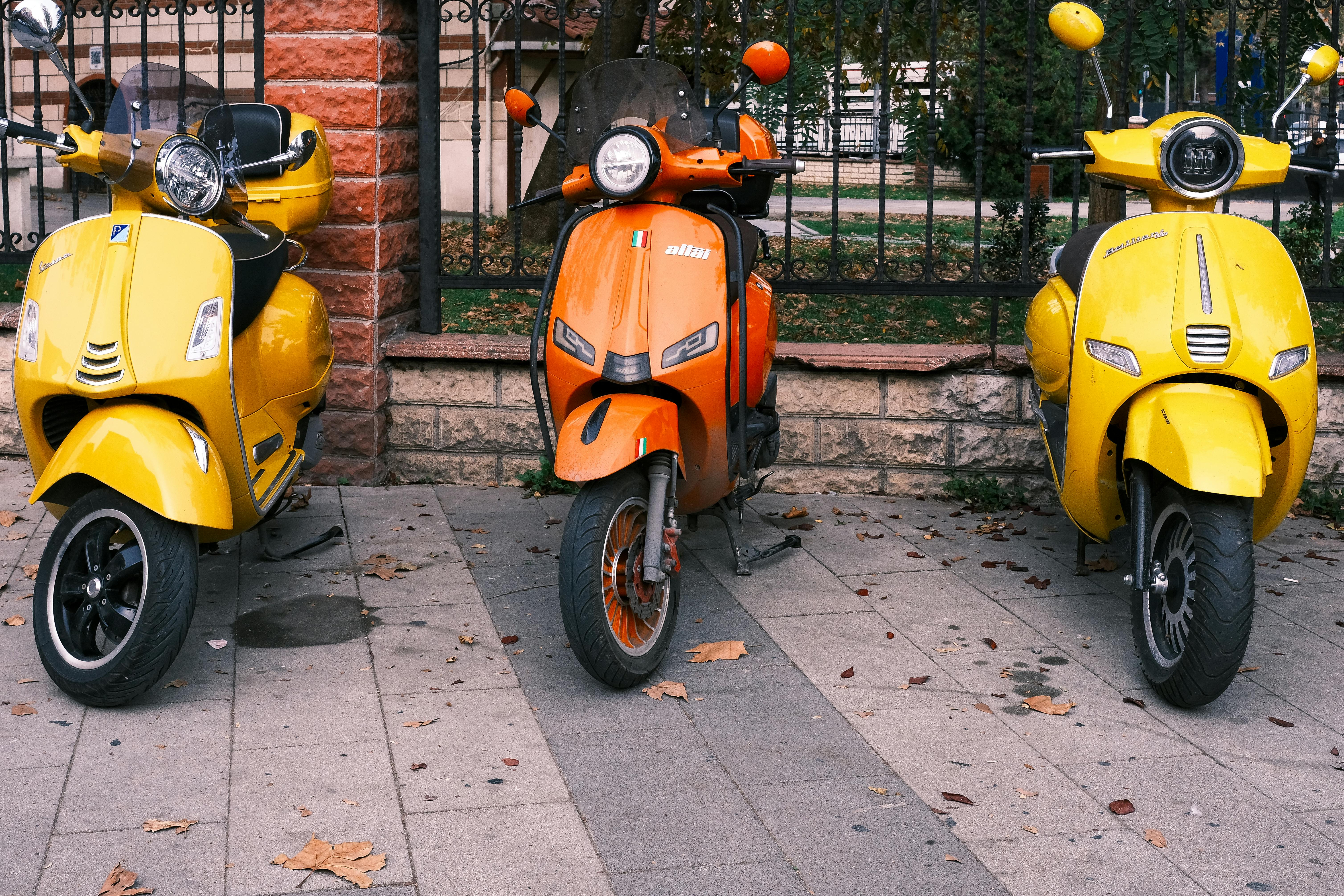 Bright yellow and orange scooters parked on a leaf-covered street in Istanbul, Turkey.