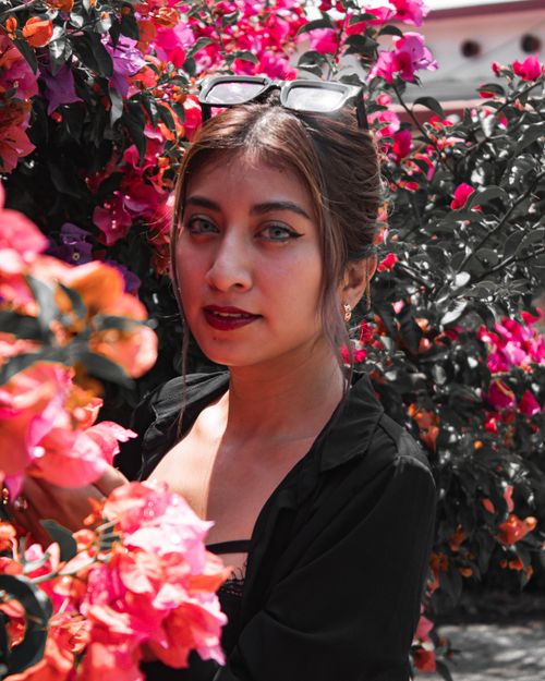 Free Young woman surrounded by colorful bougainvillea blooms in sunlight. Stock Photo