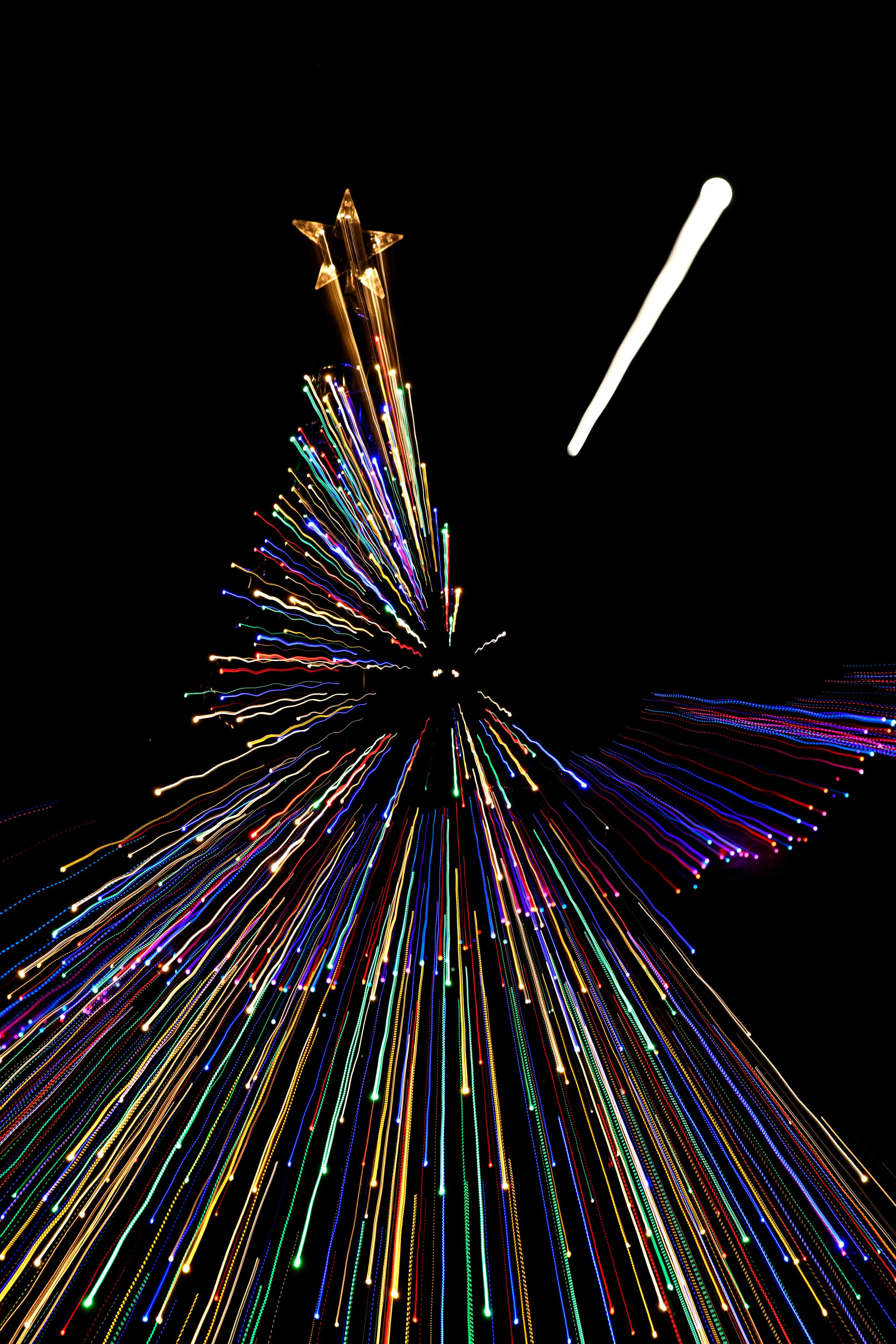 Dynamic long exposure of colorful Christmas tree lights forming abstract trails.
