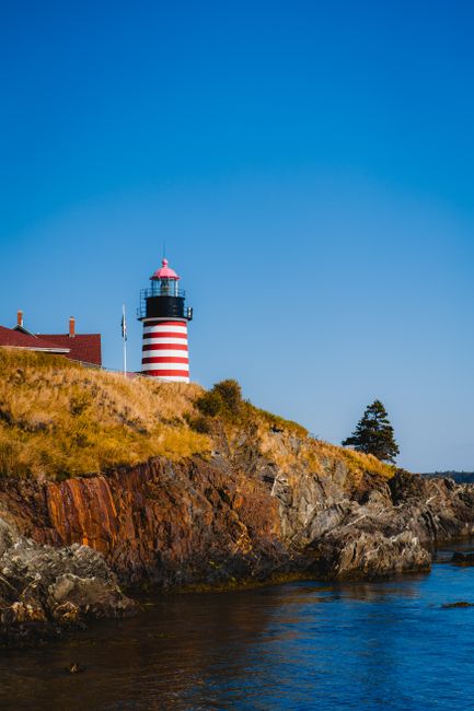 Quoddy Head Lighthouse with rocky coastline and ocean view in Maine.