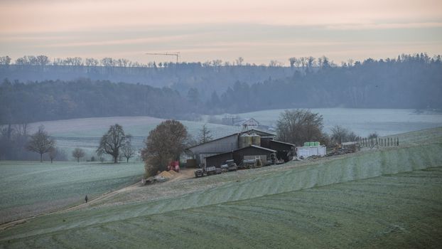 A beautiful rural farm scene at sunrise showcasing frosty fields and distant trees in a serene countryside setting.