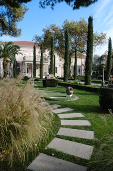 Stone pathway through lush garden leading to a luxury mansion in İzmir, Türkiye.