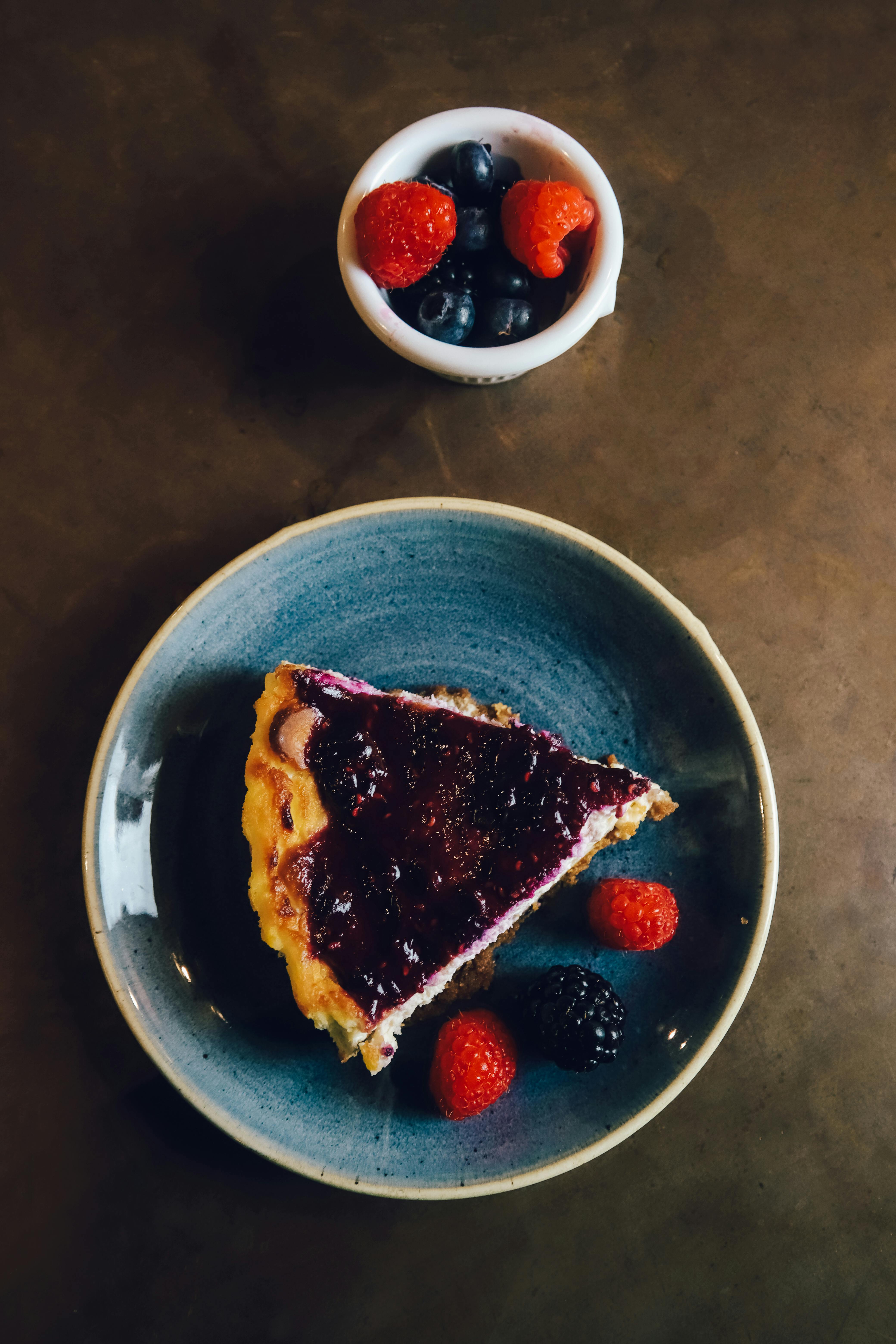 Indulge in a berry-topped cheesecake with vibrant raspberries and blueberries.