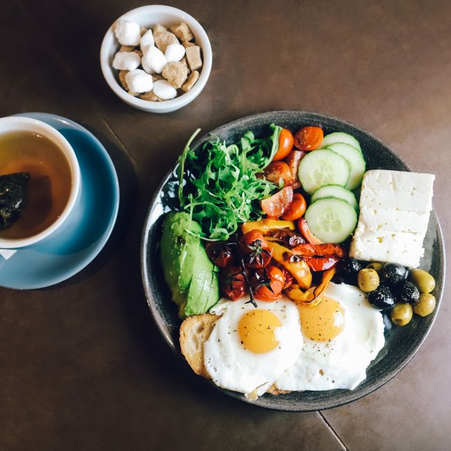 계란, 올리브, 야채, 차를 곁들인 맛있는 지중해식 아침 식사입니다.