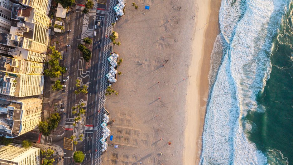 A stunning aerial shot showcasing Rio de Janeiro’s scenic beachfront at sunset, with golden sands and cityscape.