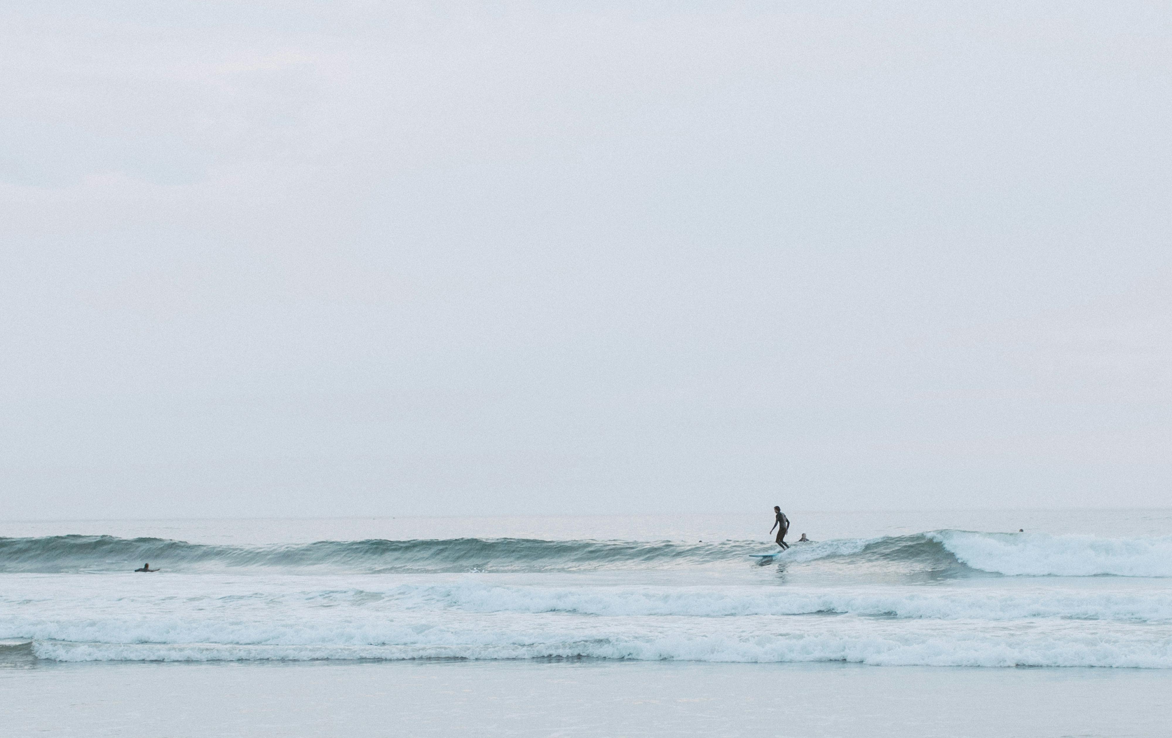 A surfer gracefully rides waves in the early morning light, capturing a tranquil ocean scene.
