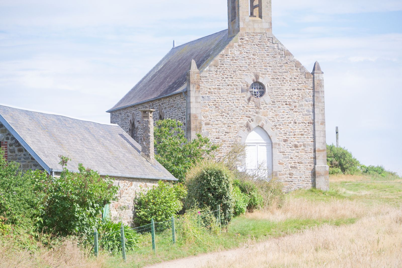 Chapelle en granit avec rosace et clocher-mur sur un coteau