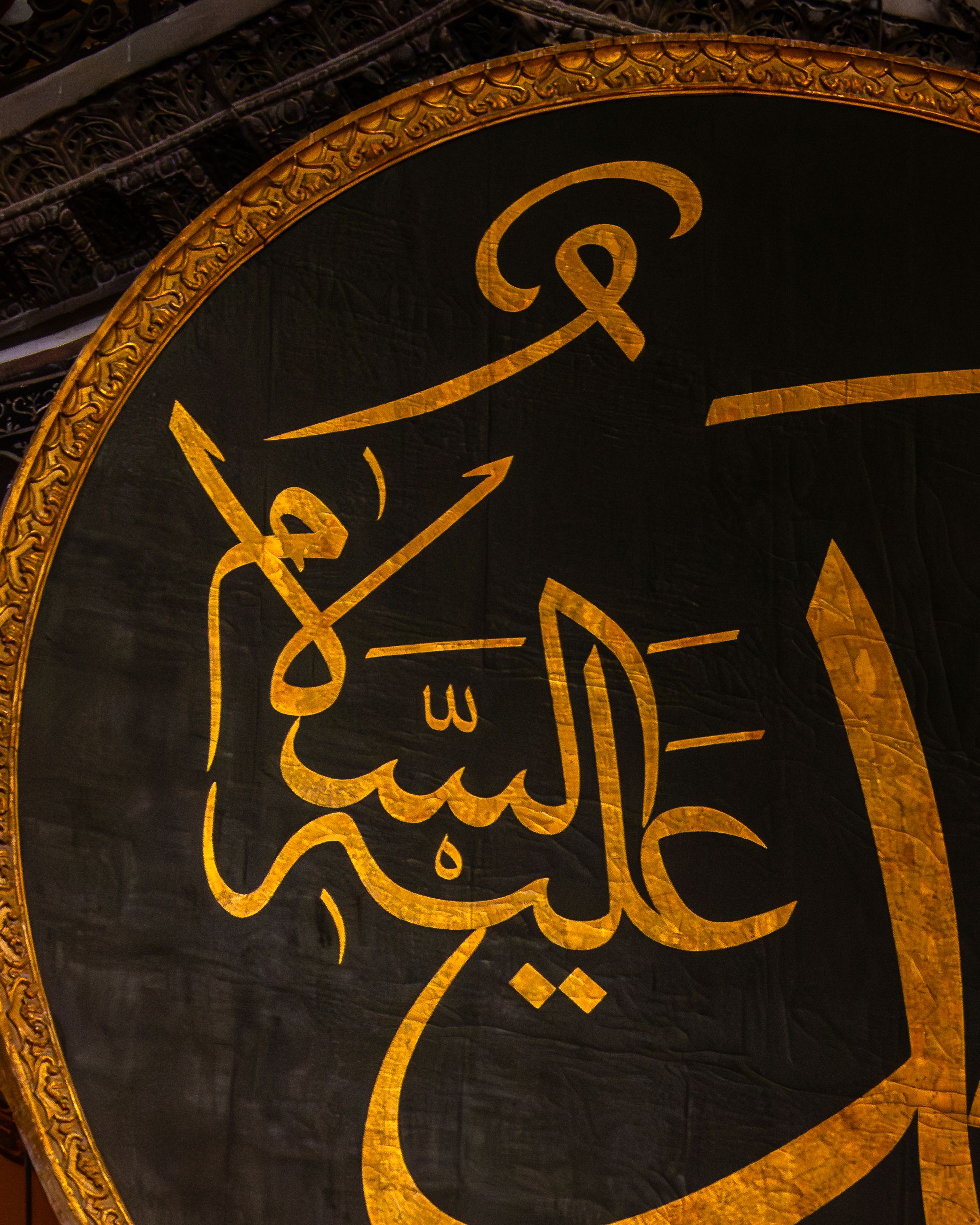Intricate Arabic calligraphy decorates a large circular panel bordered with elegant gold detailing.