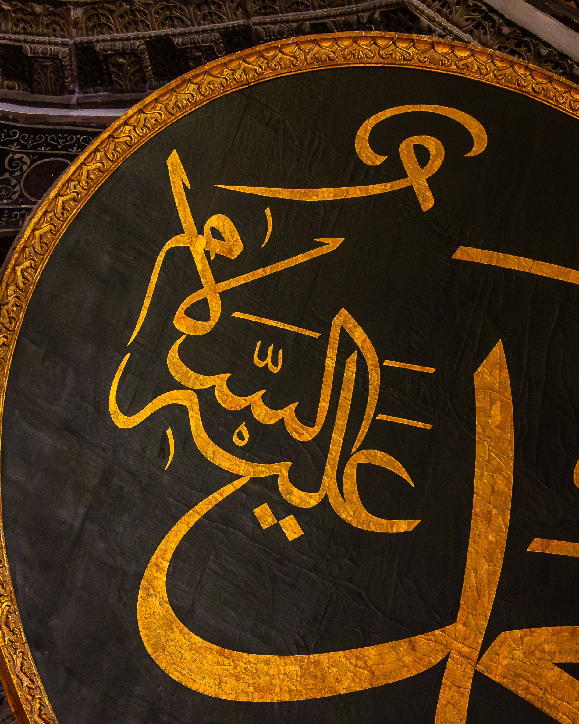 Close-up of decorative Arabic calligraphy in a golden circular frame, showcasing artistic design.