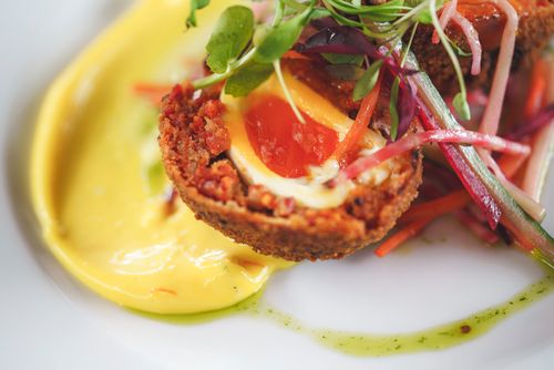 Free Close-up of a gourmet egg dish with fresh vegetables and vibrant sauce, capturing fine dining in London. Stock Photo