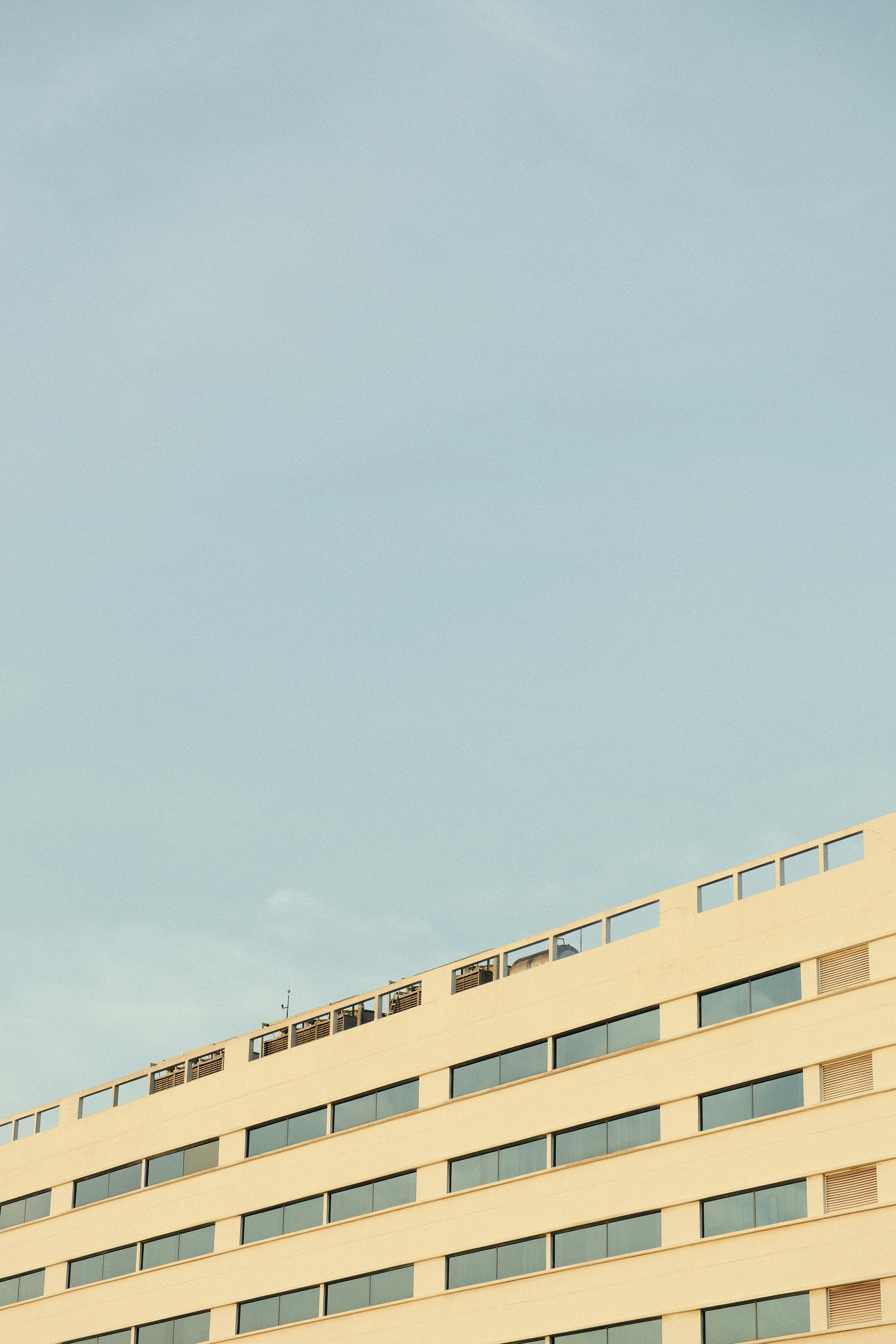 Gratuit Façade d'un bâtiment moderne se détachant sur un ciel bleu limpide, illustrant une architecture minimaliste. Photos