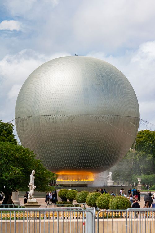 Free Large spherical structure in Paris park with statues and visitors around. Stock Photo